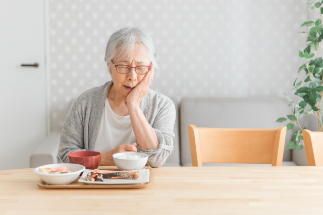 食事を食べにくそうにしているシニア女性